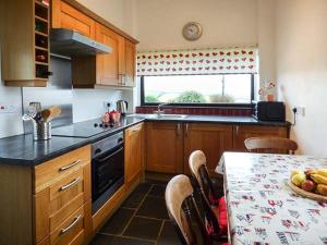 a kitchen with a table and a window and a stove at The Forge in Saint Ishmaels