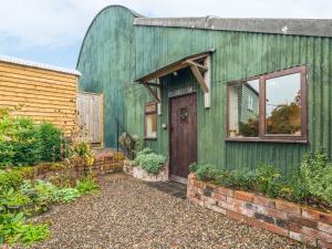 BuildwasにあるShepherd's Hutの木製のドアと窓のある緑の家