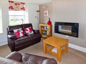 sala de estar con sofá de cuero y mesa de centro en Swallows Nest en Coniston