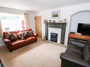 uma sala de estar com um sofá de couro e uma lareira em Manor Farm Cottage em Swaffham