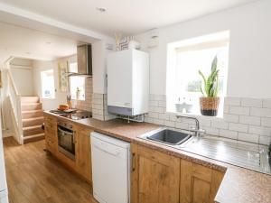 uma cozinha com armários de madeira e um lavatório em Manor Farm Cottage em Swaffham