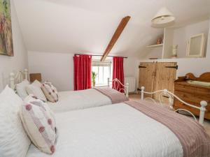 two beds in a bedroom with red curtains at Manor Farm Cottage in Swaffham