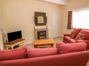 a living room with a red couch and a fireplace at Riverside Cottage in Llandrindod Wells