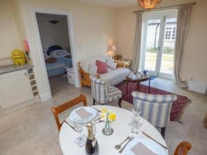 a living room with a table and chairs and a bedroom at Stable Cottage in Stonegrave