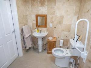 La salle de bains est pourvue de toilettes blanches et d'un lavabo. dans l'établissement Stable Cottage, à Stonegrave