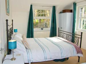 um quarto com uma cama com cortinas verdes e uma janela em Mountain View em Conwy