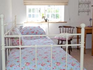 een slaapkamer met een wit bed en een sprei met bloemen bij Seashell Cottage in Deal