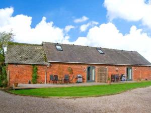 a red brick house with chairs and tables in front of it at Pear Tree Cottage in Ellesmere