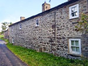 an old stone building with two windows on a street at Old Post Office in Marrick
