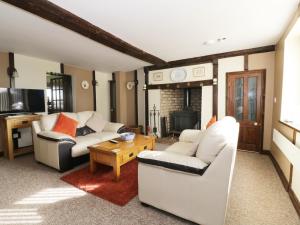 una sala de estar con 2 sofás blancos y una mesa. en Grange Farmhouse, en Hainford