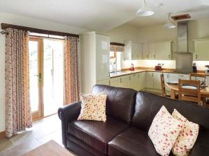 a living room with a leather couch and a kitchen at Beudy in Llangwm