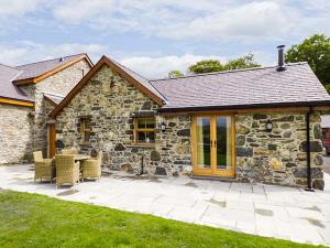 a stone house with chairs and a table in front of it at Beudy in Llangwm