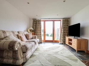 uma sala de estar com um sofá e uma televisão de ecrã plano em Longside em Abergavenny