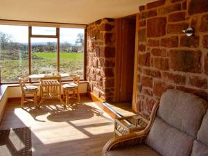 sala de estar con pared de piedra, mesa y sillas en Byre Cottage, en Nesscliffe