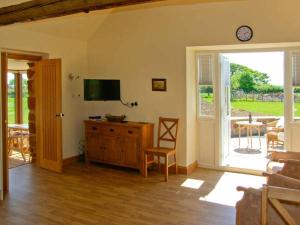 a living room with a television and a table with a chair at Byre Cottage in Nesscliffe