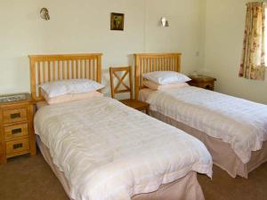 1 dormitorio con 2 camas y 2 mesitas de noche en Byre Cottage, en Nesscliffe