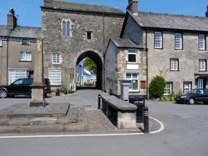 an old stone building with an arch in a street at The Byre in Grange Over Sands