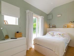 a bedroom with a white bed and a window at The Stables in Telford