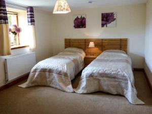 a bedroom with two beds with white blankets at Poppy Cottage in Lancaster +5 photos