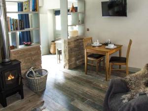 a living room with a fireplace and a table with a chair at The Stable in Ross on Wye