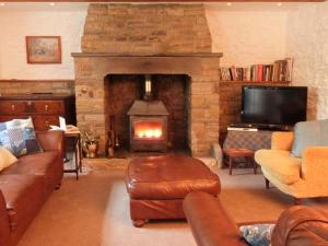 a living room with a fireplace with couches and a tv at Farrier's Cottage in Sedbergh