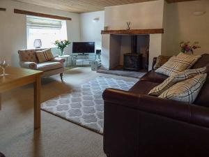 a living room with a couch and a fireplace at Bakers Cottage in Newbiggin