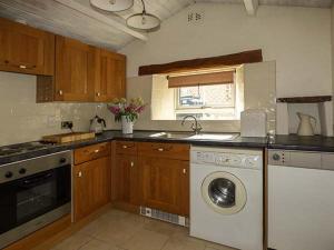 a kitchen with a sink and a washing machine at Bakers Cottage in Newbiggin