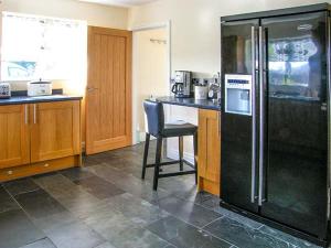 a kitchen with a black refrigerator and a chair at Hendre in Denbigh