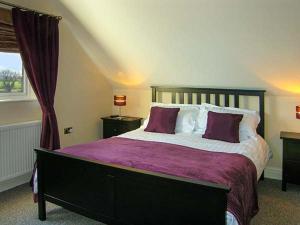 a bedroom with a large bed with purple blankets and pillows at Hendre in Denbigh