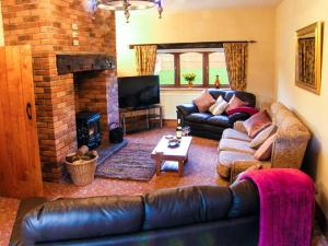 a living room with a leather couch and a fireplace at Rose Cottage in Denbigh