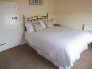 a bedroom with a large white bed with pillows at Ty Twt in Burry Port