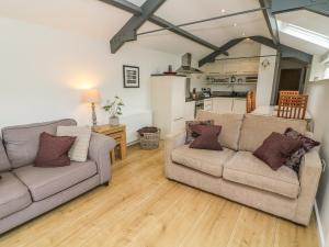 a living room with two couches and a kitchen at The Potting Shed in Carnforth