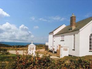 an old white church with the ocean in the background at Old Chapel in Clovelly