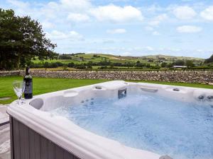 a hot tub with a bottle and a glass of wine at Ty Gwyn in Llangwm