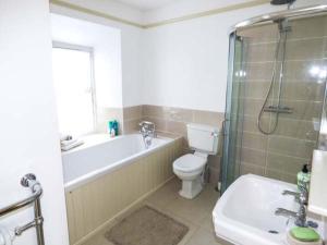 een badkamer met een bad, een toilet en een wastafel bij Rose Cottage in Cardigan