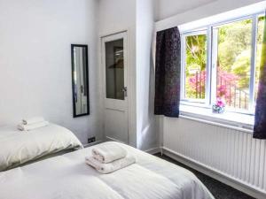 a white bedroom with two beds and a window at The Nook in Windermere