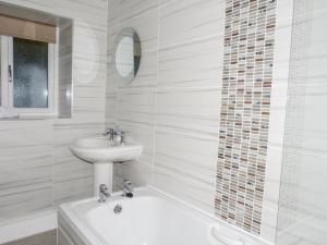 a white bathroom with a sink and a bath tub at The Nook in Windermere +7 photos