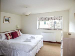 a bedroom with a white bed and a window at Kingfisher Barn in Kendal