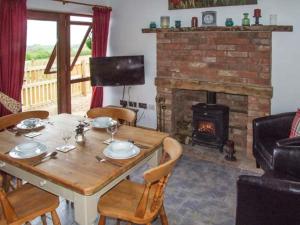 a dining room with a table and a fireplace at Owl Cottage in Southam