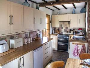 a kitchen with white cabinets and a wooden counter top at Owl Cottage in Southam