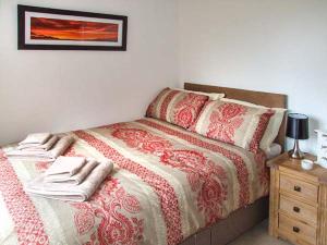 a bedroom with a bed with a red and white comforter at Owl Cottage in Southam