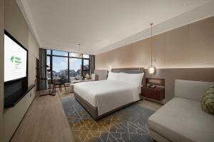 een slaapkamer met een bed en een tv en een bank bij Holiday Inn Changchun Jingyue, an IHG Hotel in Changchun