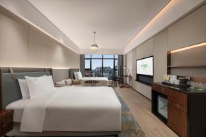 a bedroom with a large white bed and a living room at Holiday Inn Changchun Jingyue, an IHG Hotel in Changchun