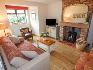 a living room with a couch and a fireplace at Beacon Cottage in Great Malvern