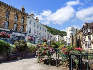 a group of buildings with flowers and a bench at Beacon Cottage in Great Malvern