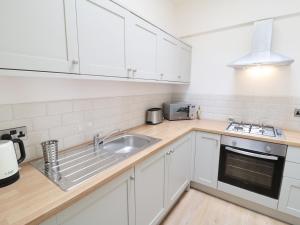 a kitchen with white cabinets and a sink at Bramble Cottage in Holmfirth