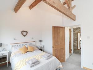 a white bedroom with a bed with pillows on it at Bramble Cottage in Holmfirth