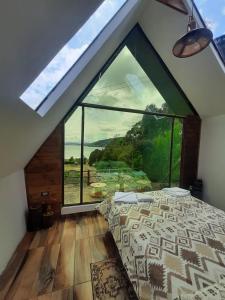 a bedroom with a bed and a large window at Cabaña Santo Domingo in Cuítiva