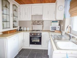 a kitchen with white cabinets and a stove and a sink at Chapel Cottage in Whitby