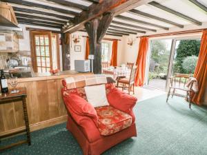 a living room with a red couch and a kitchen at White Cottage in Hopton Wafers